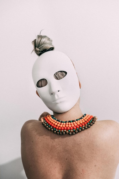 rear view of topless woman wearing mask against wall