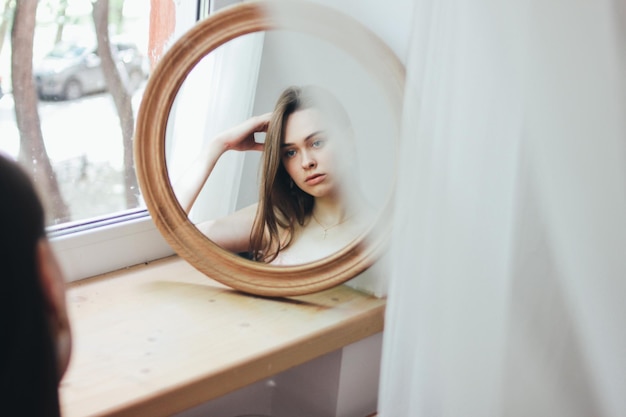 Reflection of beautiful woman on circular mirror at home