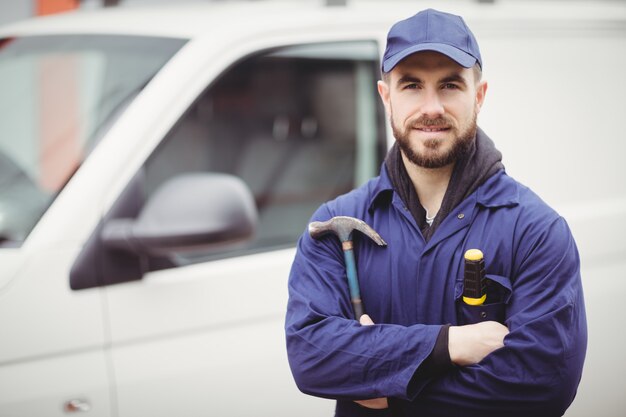 Reparatør holder en hammer foran varebilen sin