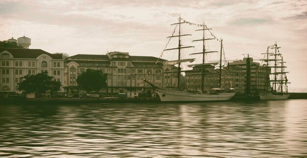 sailboats in sea against buildings in city
