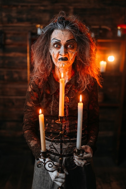 Scary witch with candlestick and cane reads spell