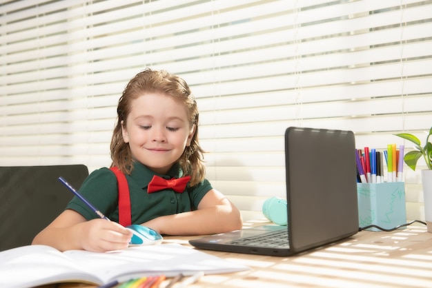 schoolboy studying and using computer laptop and writing on notebook nerd pupil