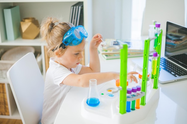 Science Little cute girl sets up experiments at home colored liquids laboratory childs installation