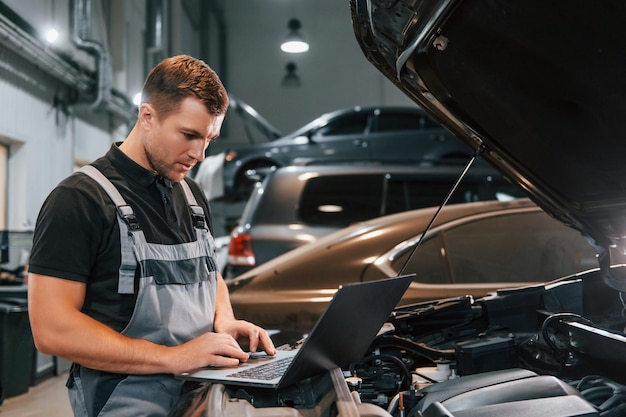 Side view Man in uniform is working in the auto service