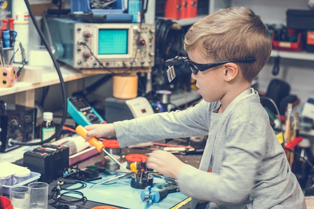 side view of boy repairing equipment on table in workshop