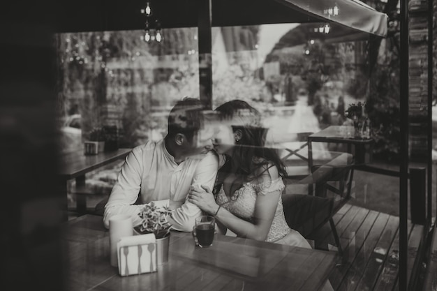 side view portrait of a loving european couple laughing while enjoying a date in a cafe black and white photo
