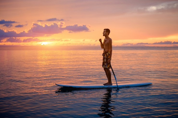 Foto silhouette of man paddleboarding at sunset
