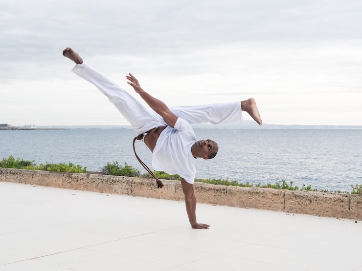 Foto skilled brazilian male practitioner in action demonstrating traditional capoeira by the seaside