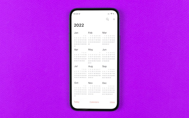 Smartphone with calendar 2022. Business workspace, purple background. Top view photo
