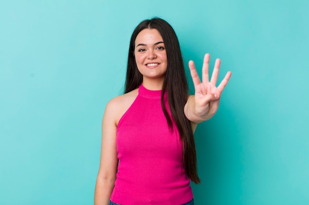 Smiling and looking friendly showing number four or fourth with hand forward counting down