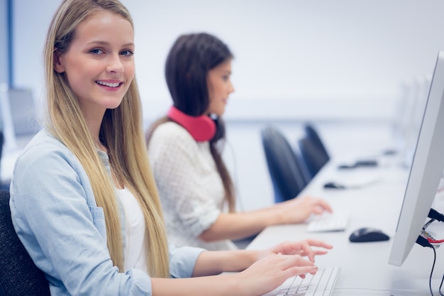 Smiling students using computer at university 