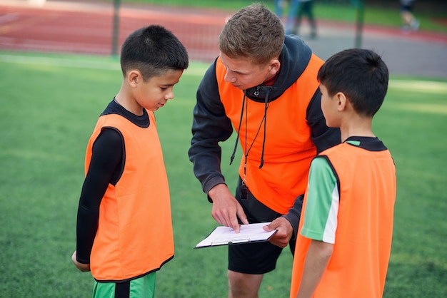 Soccer coach shows a strategy of football game to his players at training.