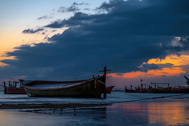 Solnedgang med skyet himmel på Gadani-stranden med dhow-båt