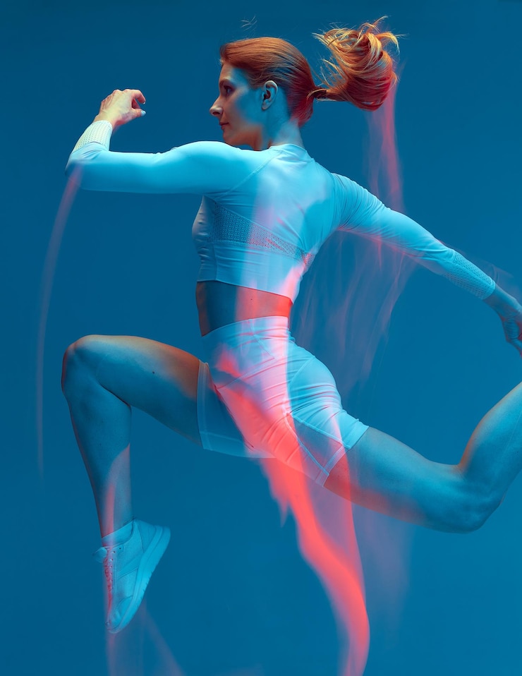 Foto sporty girl running in white tracksuit on blue background isolated fitness model in studio with