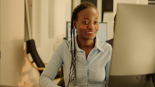 startup employee working on computer in office with big windows, using data research to create business report. planning management paperwork for web presentation, freelancer work.