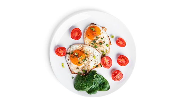 Stekte egg med grønnsaker på hvit tallerken isolert på hvit bakgrunn. Vakker frokost. Høy kvalitet foto