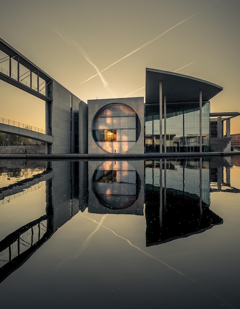 Symmetry view of buildings by artificial pond against sky during sunset