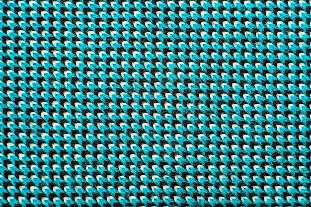 synthetic knitted fabric with pattern elements of blue, black and white yarns close up. multicolor patterned knitted fabric texture. background