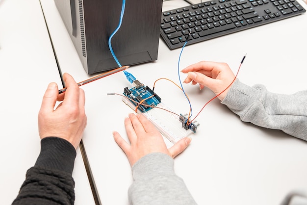 Teacher helping his teen student with diy robot on stem education classStudent In After School Computer Coding Class Building And Learning To Program Robot VehicleArduino Ultrasonic installation