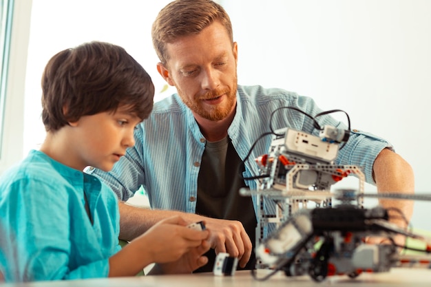 teacher supporting a pupil turning on a robot
