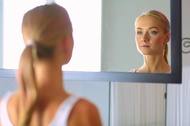 The beautiful young girl with a clean fresh skin touches with a hand a cheek