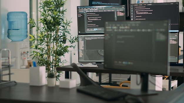 Tomt skrivebord med flere skjermer som viser serverkode og programmeringsspråk, kompilering i programvareutviklingsbyråets kontor. System for nettskybasert databehandling av algoritmer for online databaser.