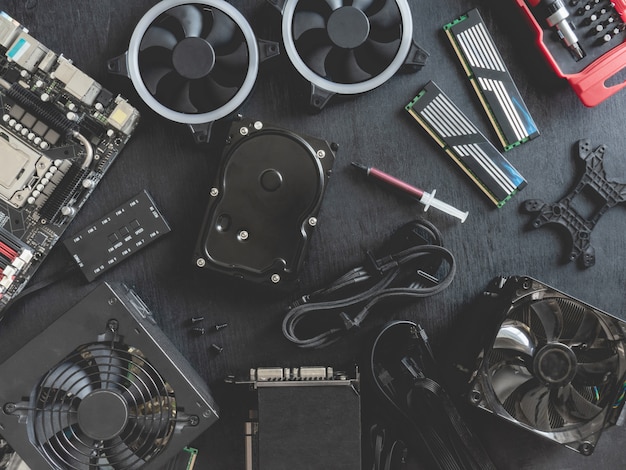 top view of computer parts with harddisk, ram, cpu, graphics card, and motherboard on black table background.
