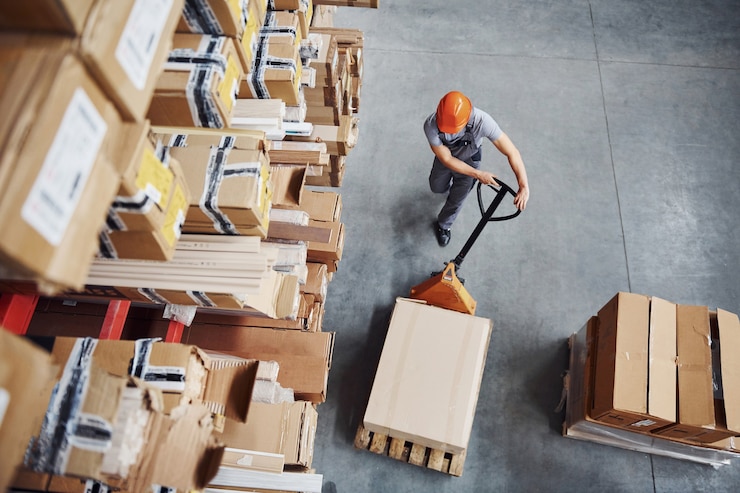 Foto top view of male worker in warehouse with pallet truck.