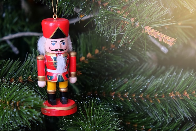Toy funny nutcracker hanging on Christmas tree.