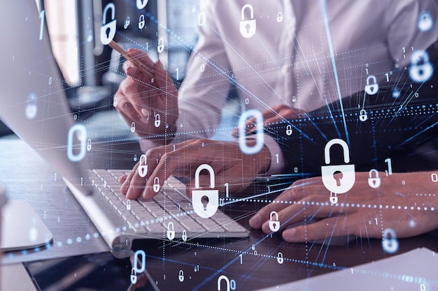 Two businesspeople in formal wear working on the project to protect cyber security of international company using laptop Padlock Hologram icons Teamwork concept
