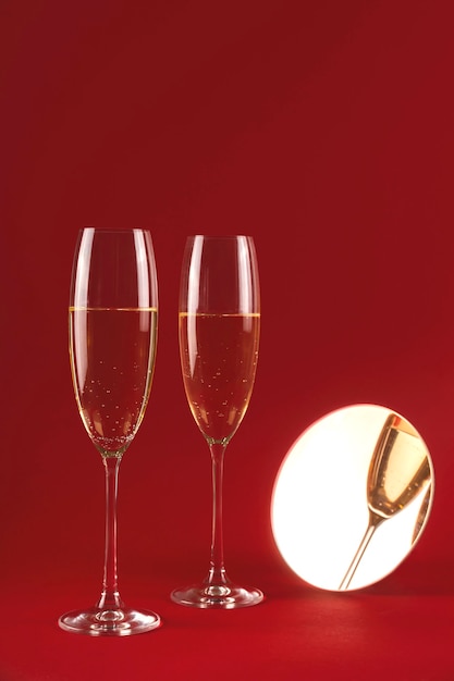 Two glassess of champagne with reflection in a small round mirror on a red