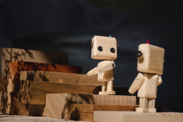 Two small wooden robots climb up a ladder of wooden blocks mutual assistance concept