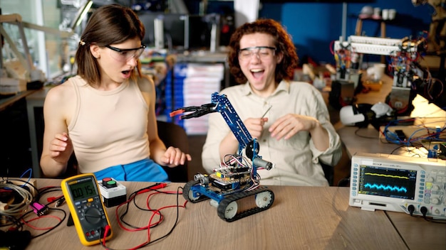 two young happy engineers fixing a mechanical robot car in the workshop using vr virtual reality