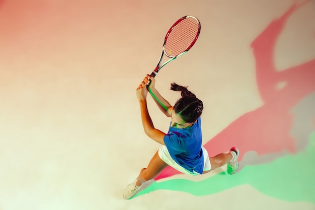 Ung kvinne i blå skjorte spiller tennis Hun slår ballen med en racket