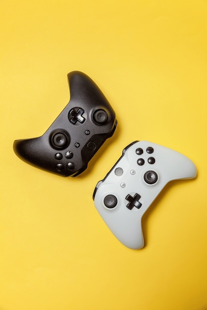 White and black two joystick gamepad, game console on yellow