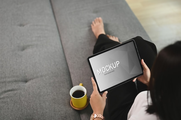 woman is relaxing with tablet while lying down on couch in living room