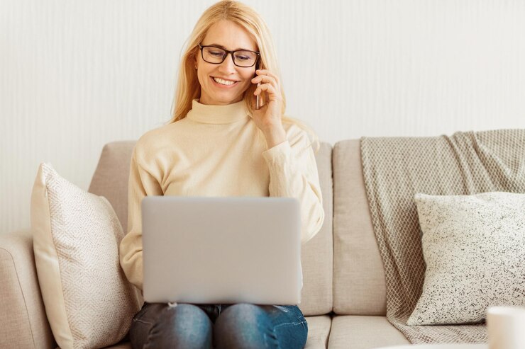 Foto woman working on laptop and phone on sofa