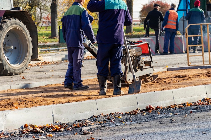 Foto worker compresses sand for paving slabs with special working tool - tamping machine or vibratory plate. repair of pavement pavement. preparation of the surface for laying paving slabs.