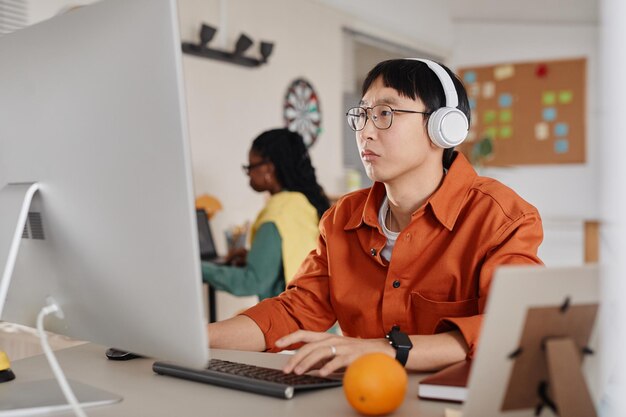 Working at office with headphones and computer monitor