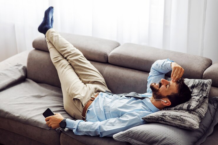Foto young attractive businessman lying on couch at home, relaxing and using smart phone.
