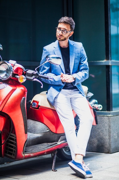 Young businessman looking away while sitting on motor scooter