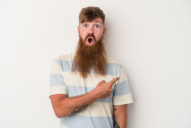 young caucasian ginger man with long beard isolated on white background pointing to the side
