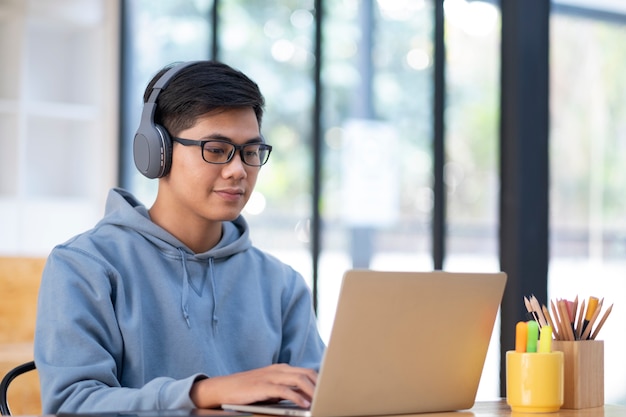 young collage student using computer and mobile device studying online.
