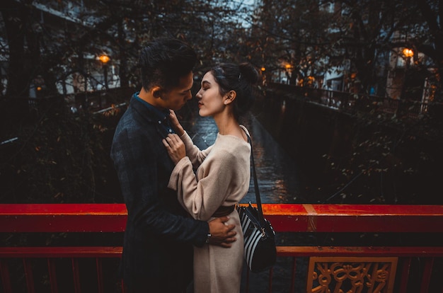 young couple standing on bridge at night