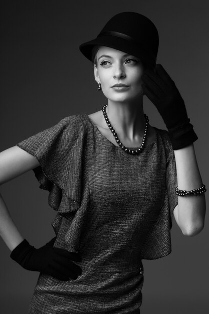 young elegant woman, retro fashion, hat, gloves, dress. black and white image.