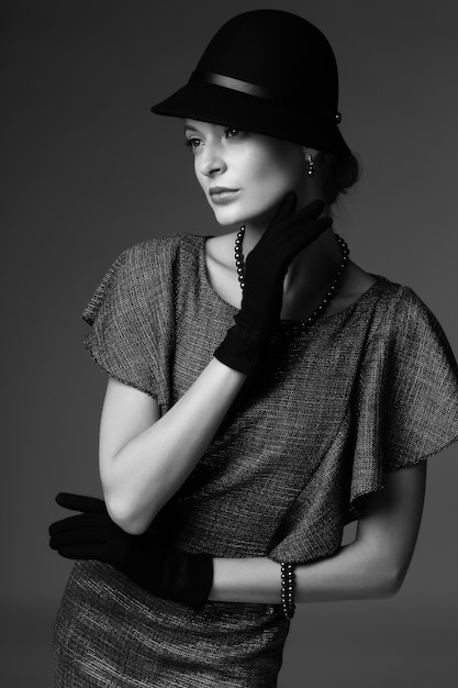 young elegant woman, retro fashion, hat, gloves, dress. black and white image.