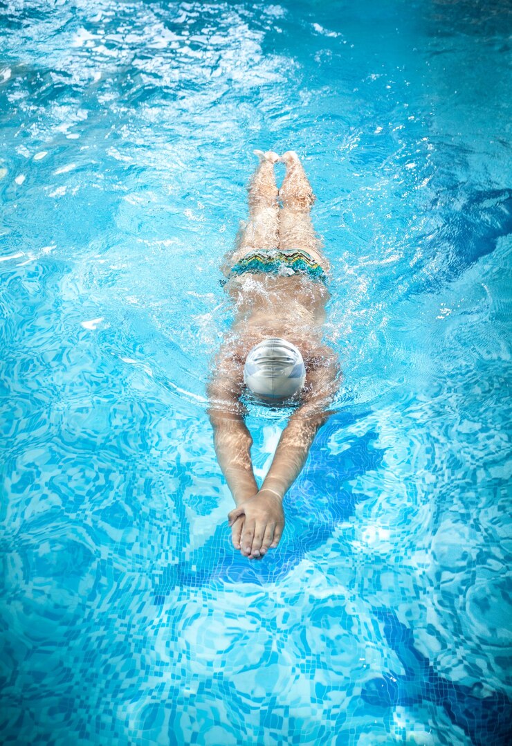 Foto young man in goggles swimming under water at swimming pool