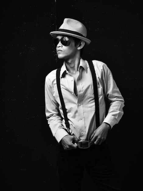 Young man wearing hat standing against black background