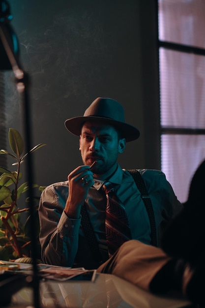 Young pensive man in hat and formalwear holding cigarette