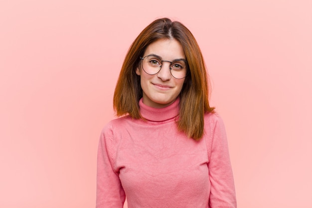 Young pretty woman smiling positively and confidently, looking satisfied, friendly and happy over pink wall